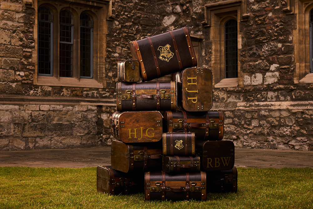 A pile of different Hogwarts trunks on a lawn
