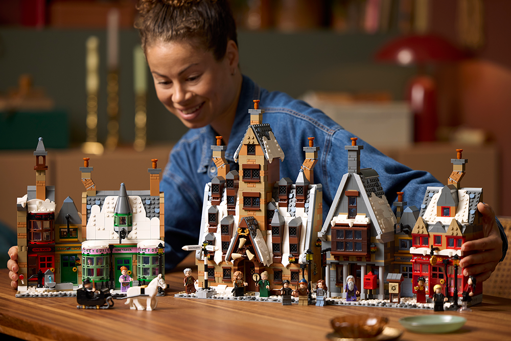 A built LEGO Hogsmeade Collectors Edition on a table in front of smiling woman